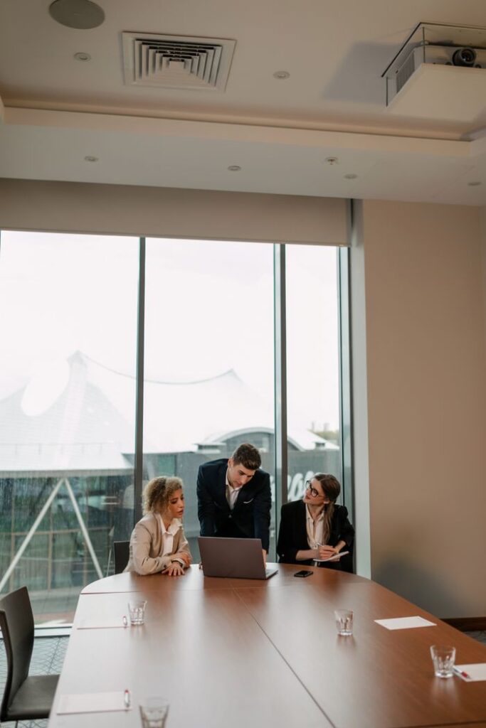 Business colleagues in a modern conference room discussing ideas at a meeting table with a laptop.