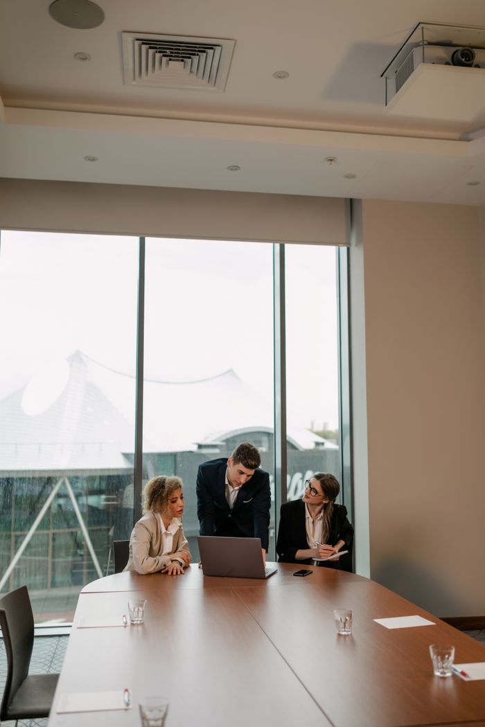 Business colleagues in a modern conference room discussing ideas at a meeting table with a laptop.