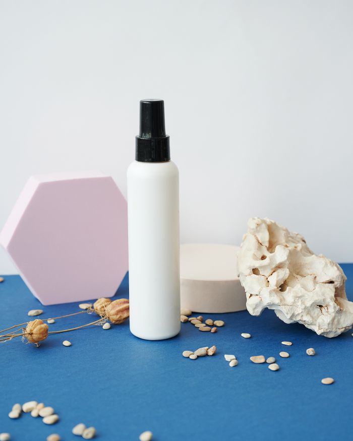 Stylish composition featuring a cosmetic spray bottle with decorative elements.